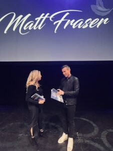Maile Navarro hands Matt Fraser her children’s book ‘Zuma’s Magical Balloon’ during a spiritual meet and greet at The Wiltern in Los Angeles.
